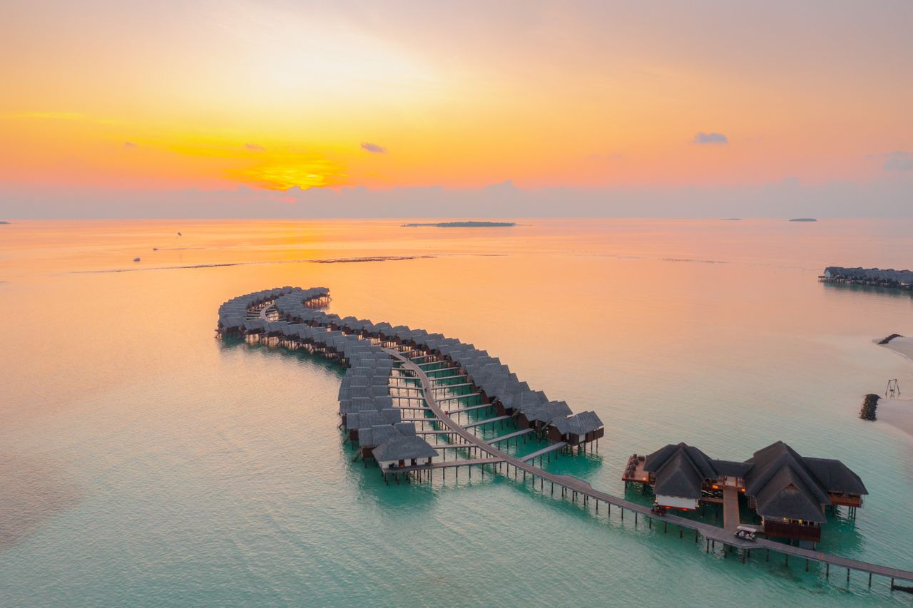 Services A stunning aerial view of overwater bungalows during sunset in Maldives, highlighting serene ocean views.