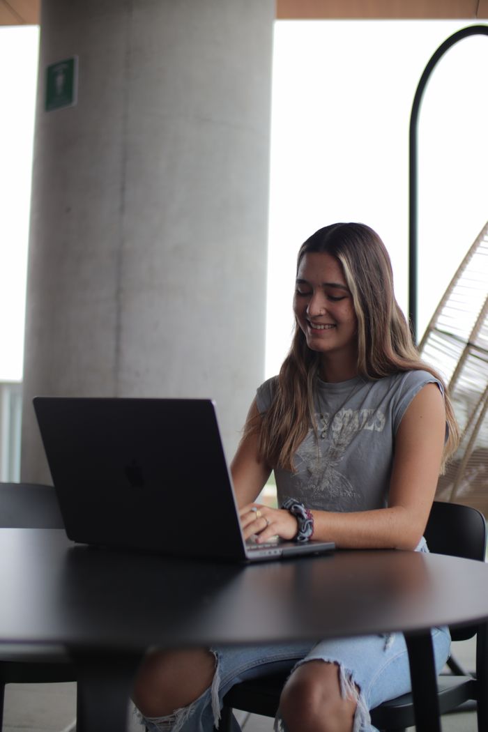 Services Young woman using a laptop in a modern indoor setting, focused on online study.