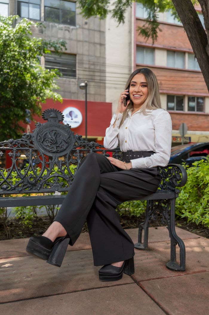 Services Confident businesswoman in park, CDMX, on phone, smiling.