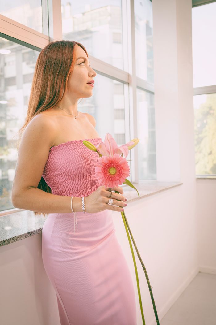 Services Elegant woman in pink dress holding a flower indoors in Buenos Aires.
